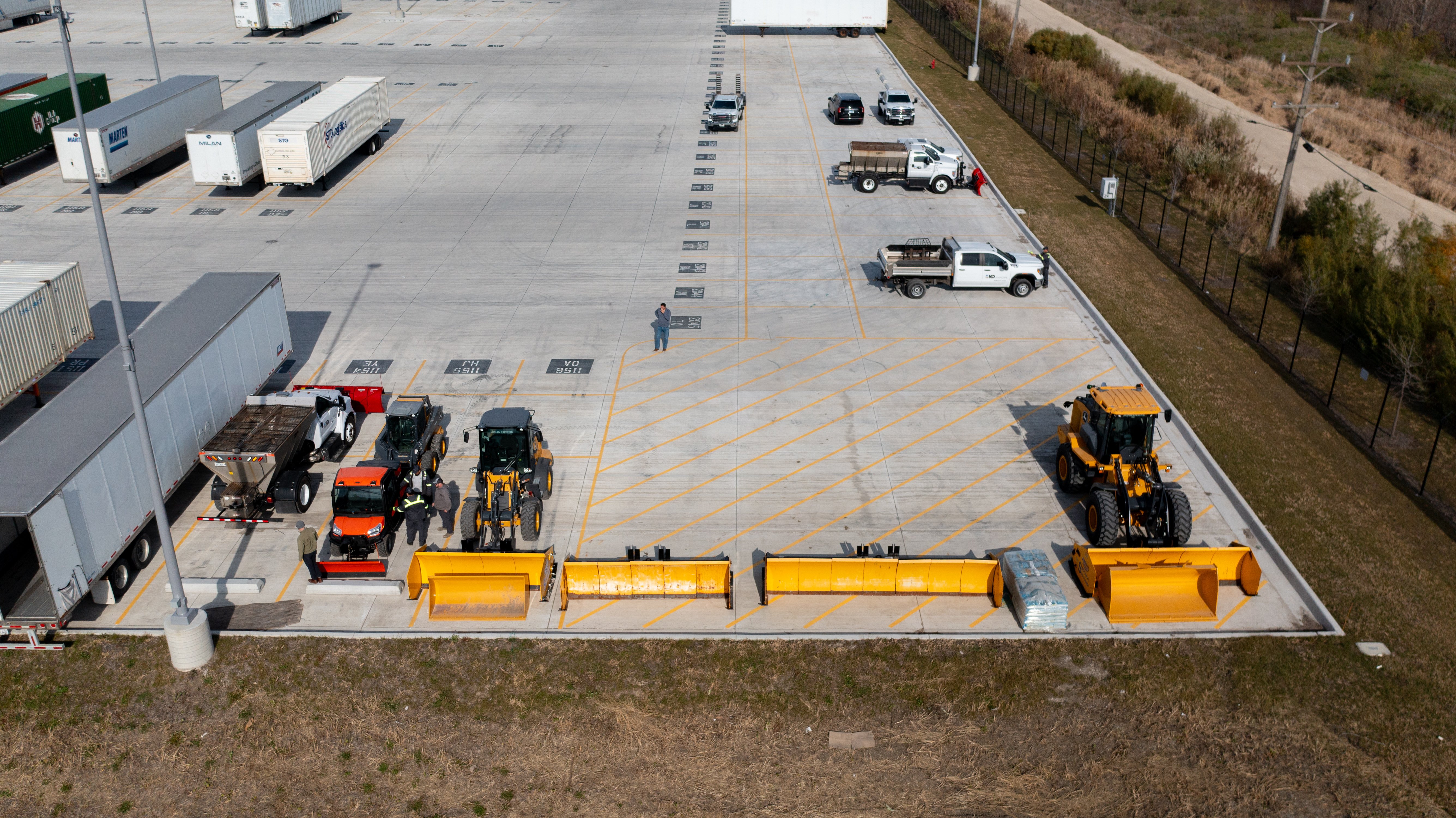 industrial warehouse parking lot aerial snow equipment before a storm