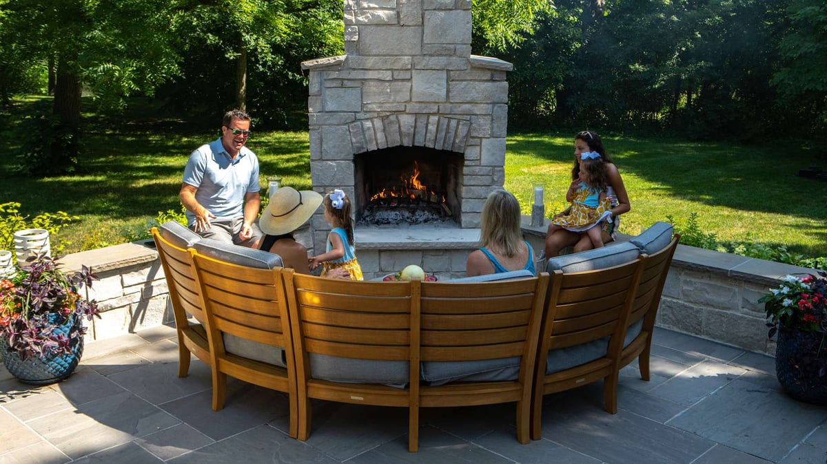 family sitting outside on couch in front of fireplace