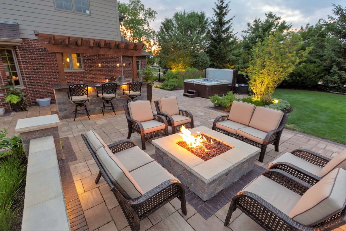 firepit with seating on patio and pergola with outdoor kitchen and bar
