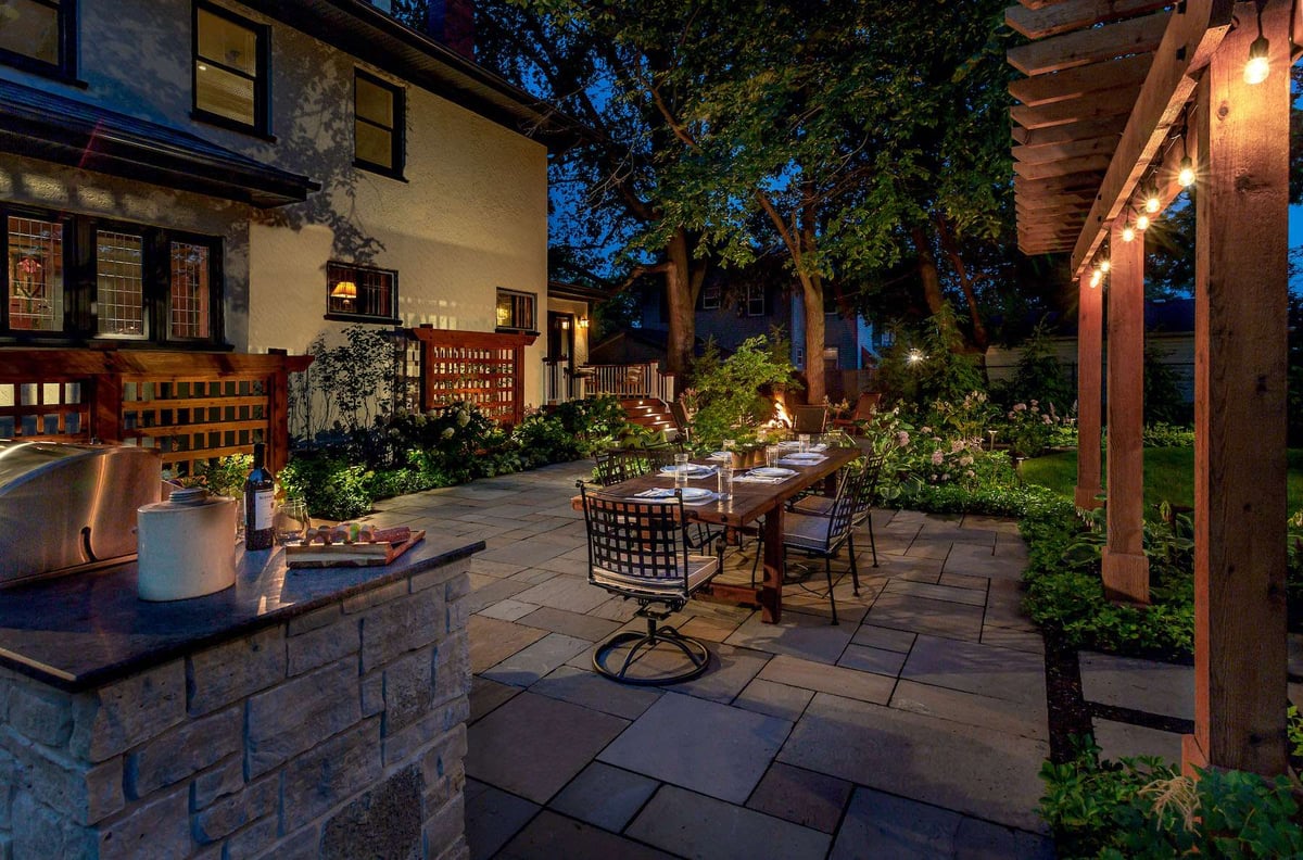 landscape lighting around bluestone patio with outdoor kitchen