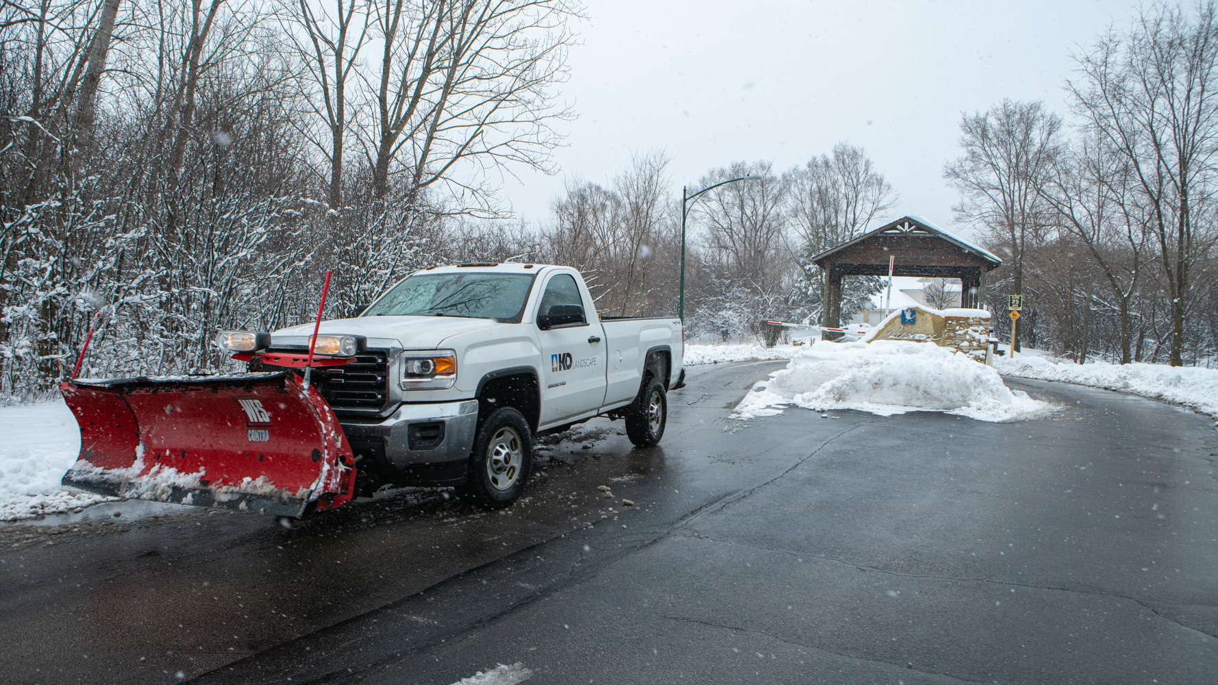 commercial snow removal truck with plow at a cleared HOA entrance
