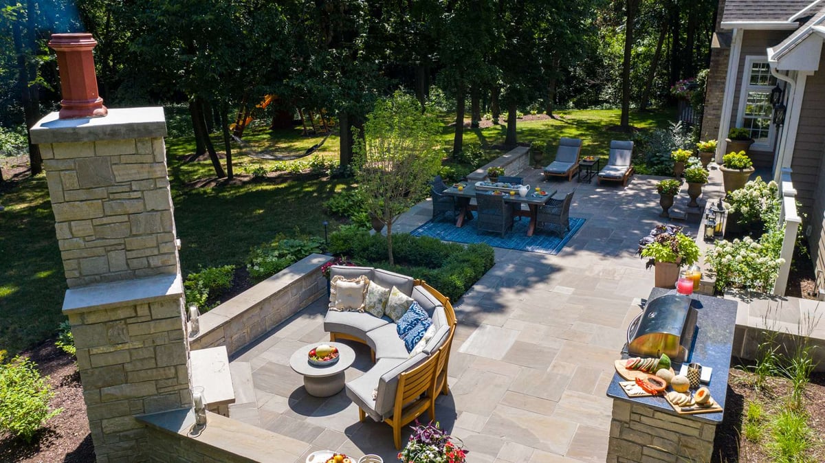 aerial view of outdoor fireplace on patio with outdoor kitchen and seating area