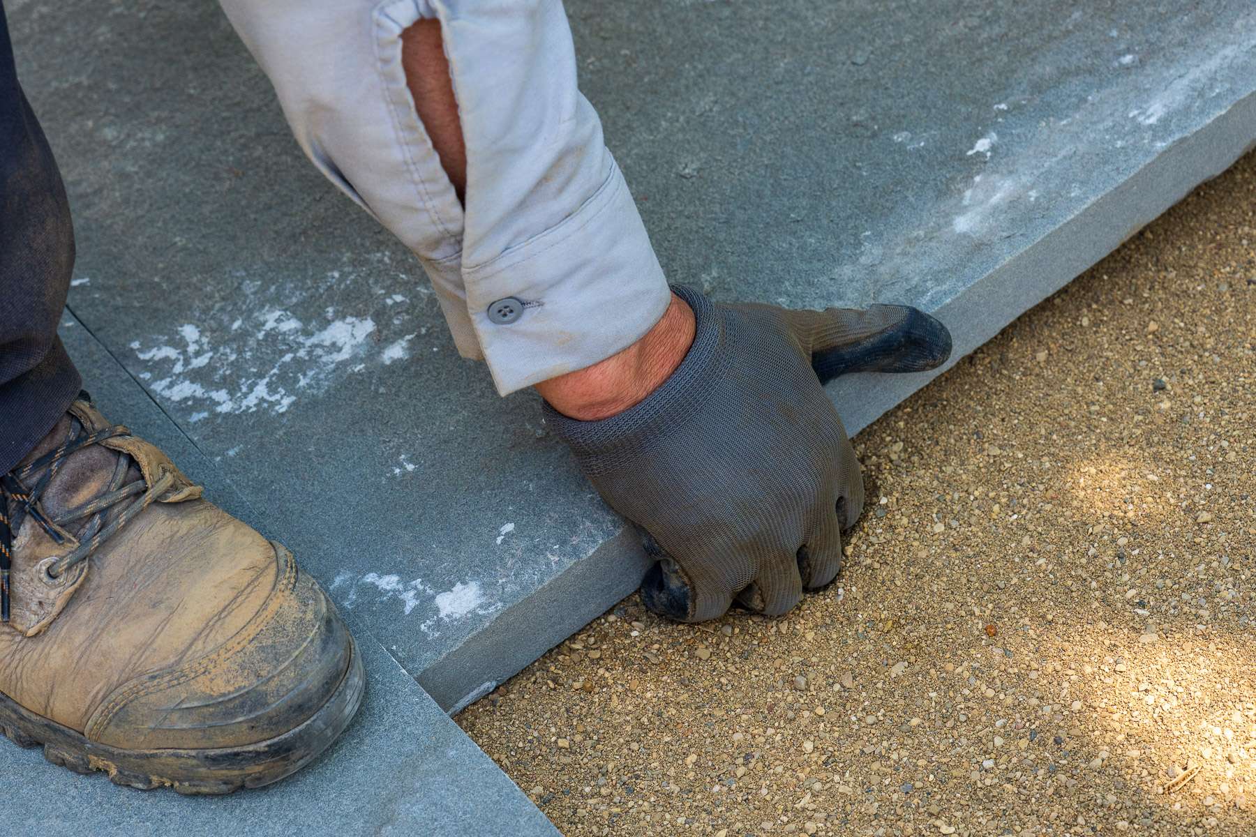 hardscaping technician installing a slab paver patio over a sand base