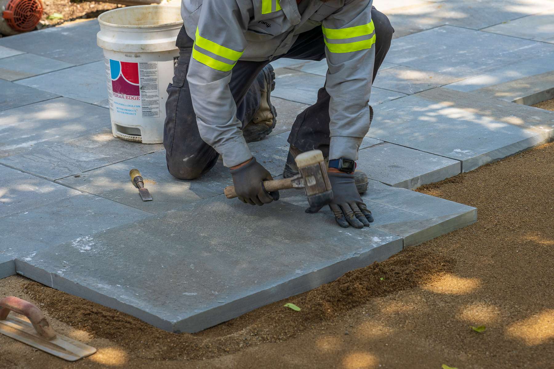 landscape construction technician hardscape installation technician installing large slab pavers for a commercial property