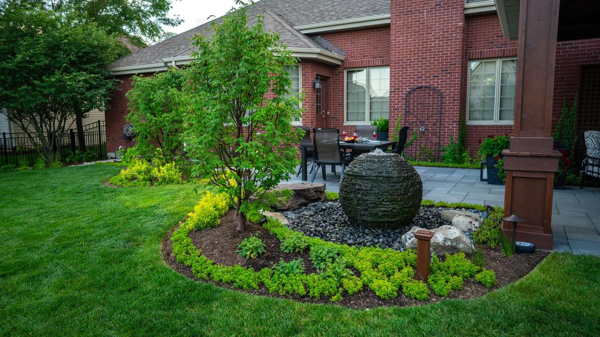 water feature with plantings in landscape bed near patio