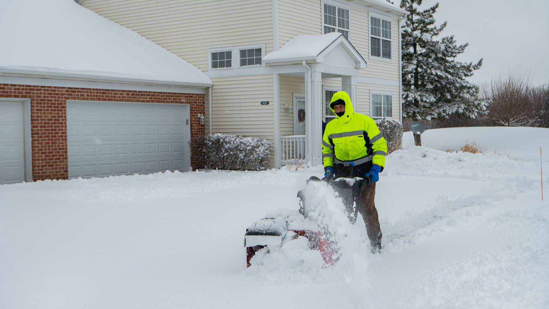 commercial snow removal technician running a snowblower on an HOA sidewalk
