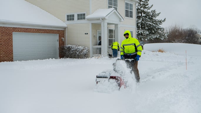 commercial snow removal team member using snowblower on HOA walkway