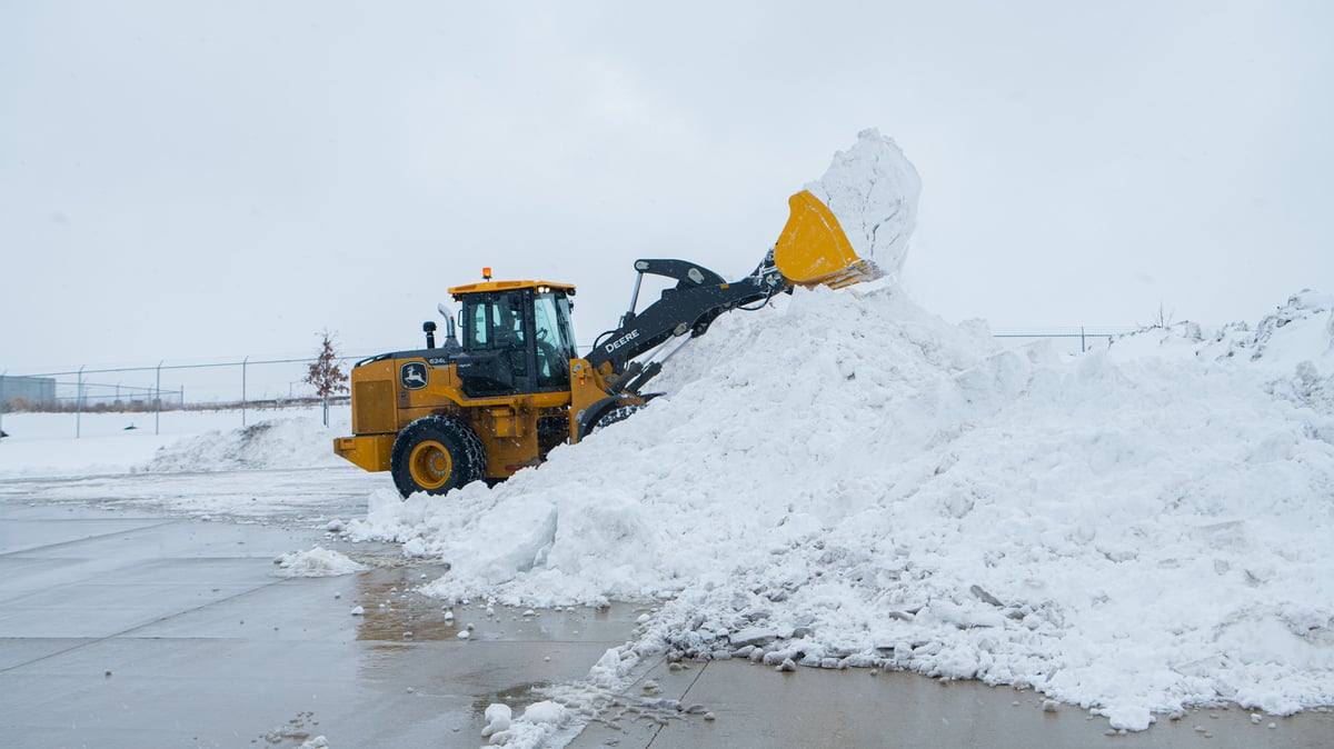 front loader piles snow in parking lot