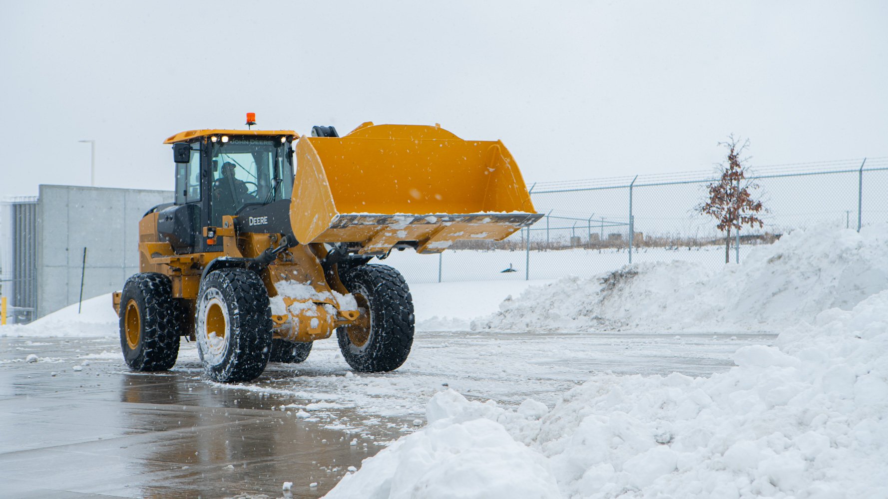 plow loader moving large piles of snow on a commercial facility parking lot