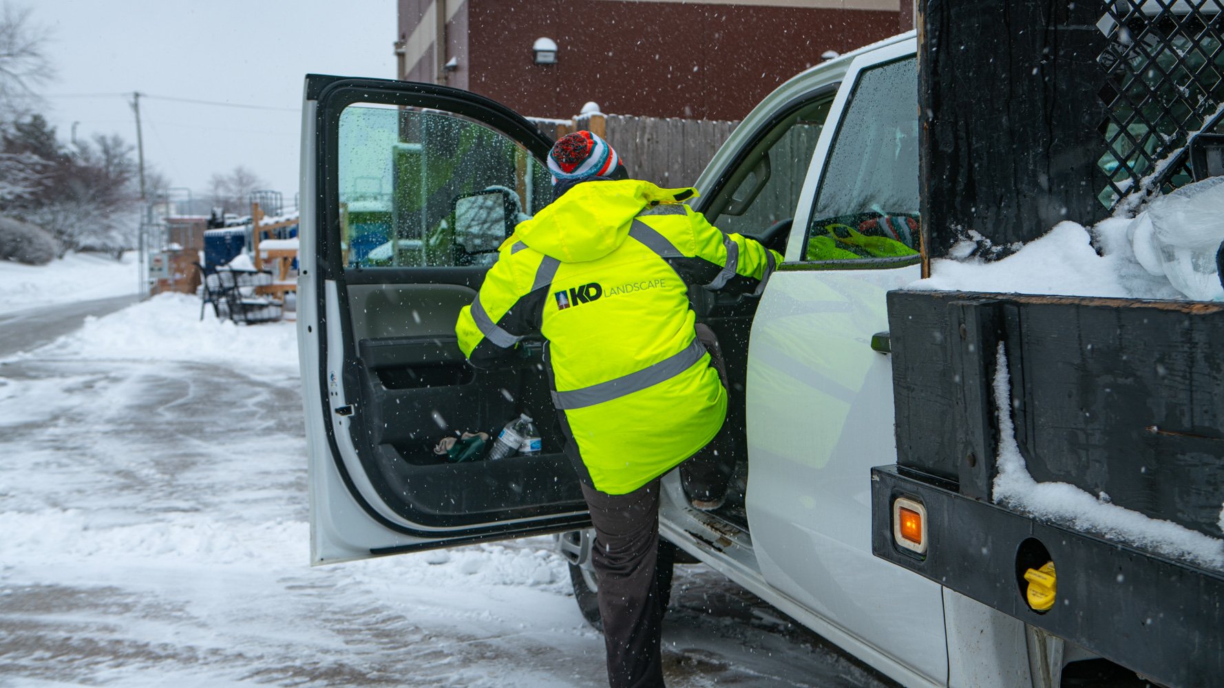 commercial snow removal technician entering a crew truck during a snowstorm