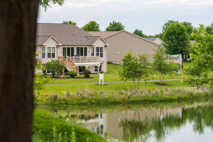 commercial HOA pond with trees homes in background