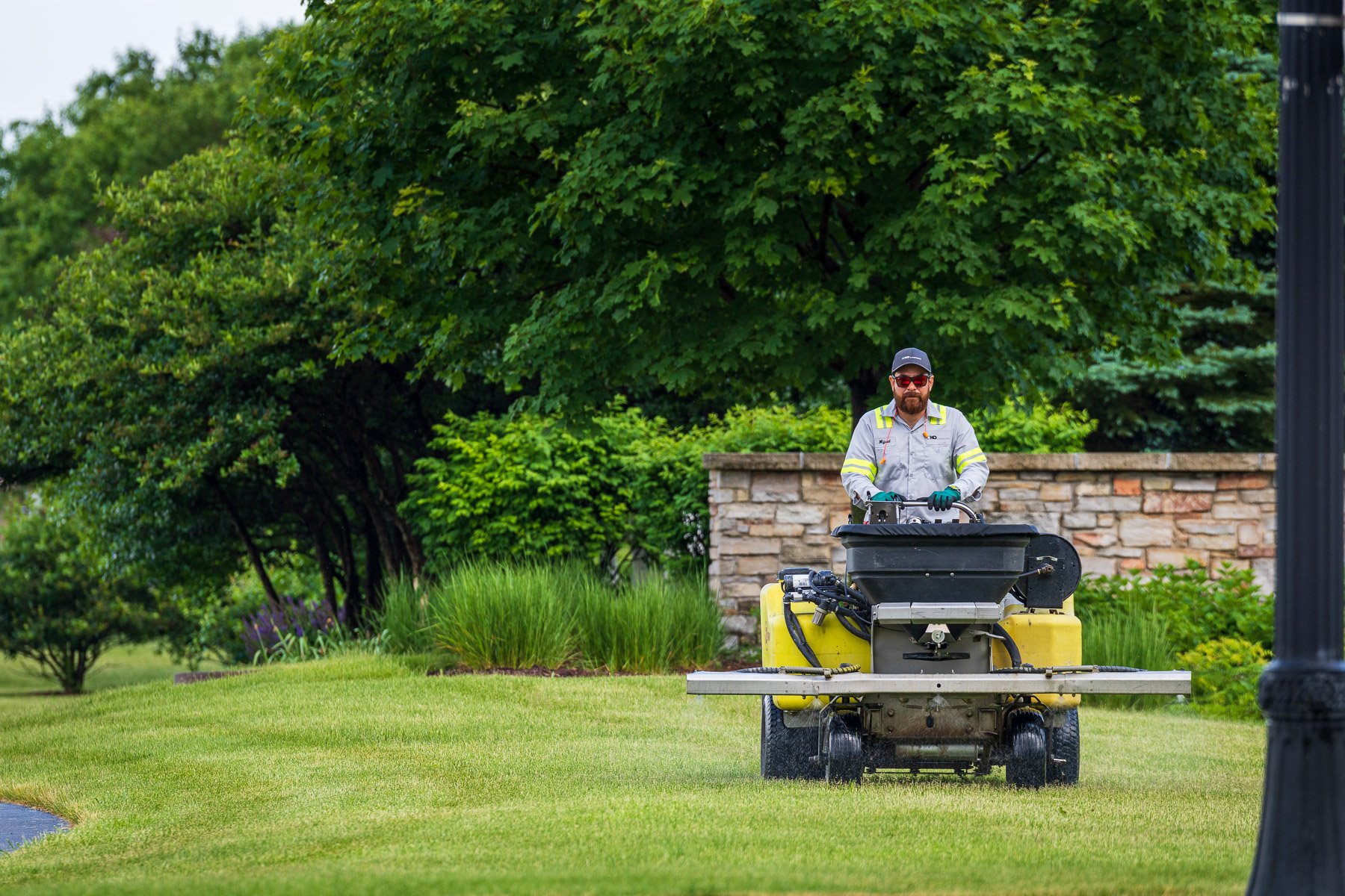 commercial lawn care technician spraying lawn with liquid fertilizer
