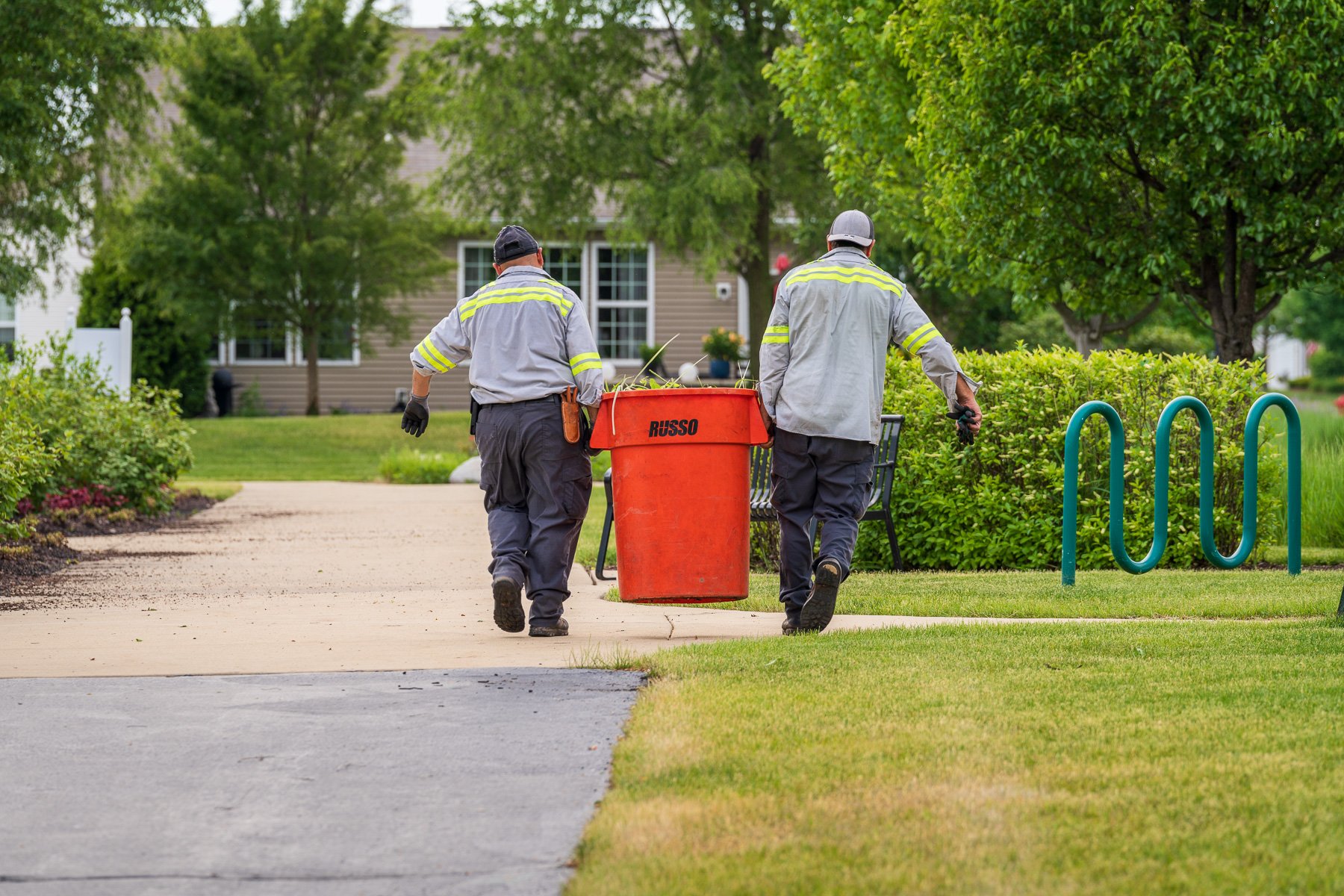 commercial landscape maintenance technician cleaning up commercial property grounds