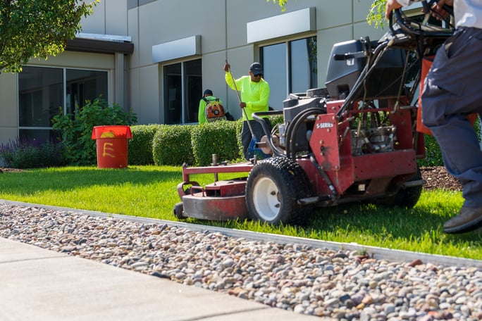 landscape maintenance team mows grass at commercial building