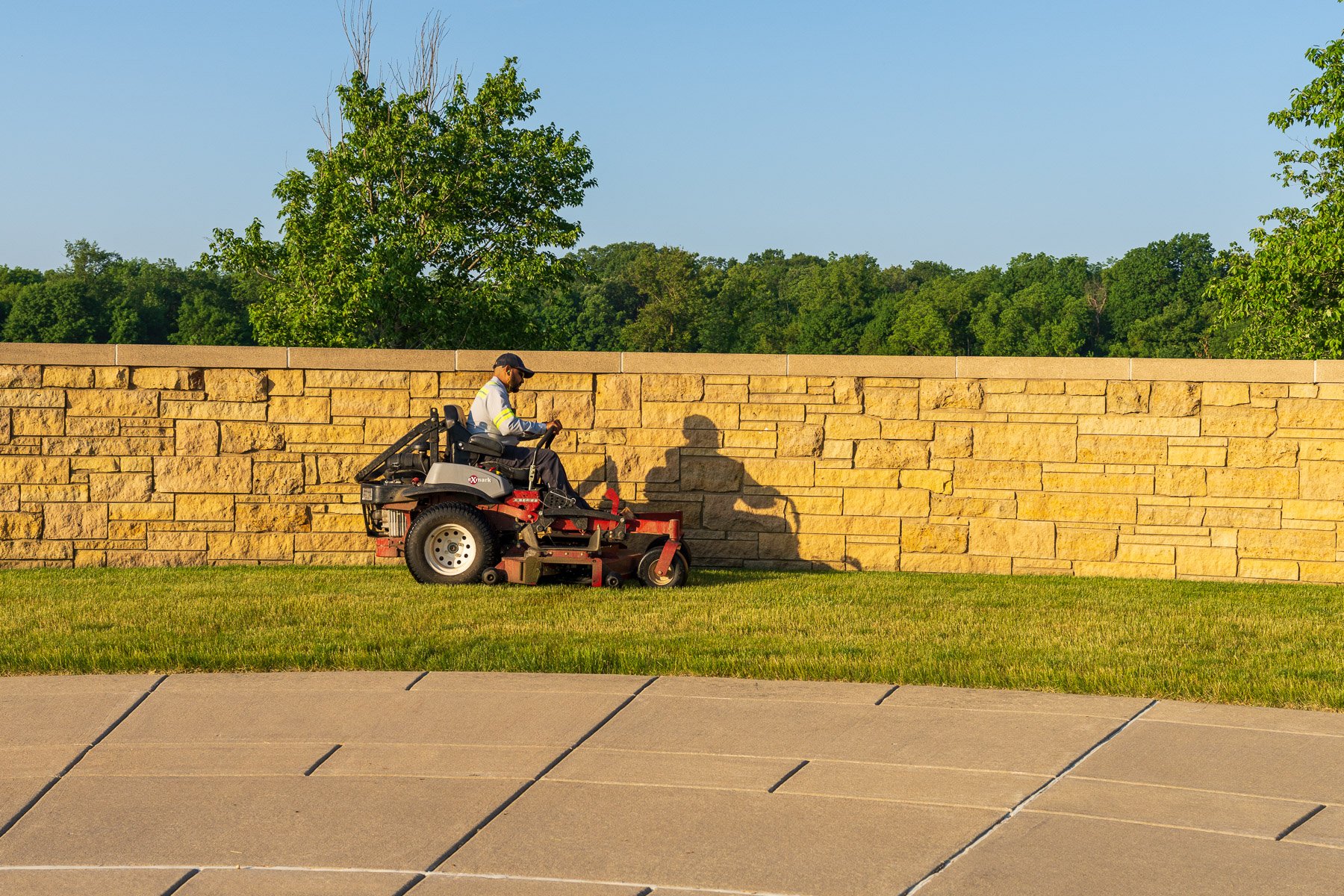 commercial maintenance technicians mowing near a monument at a commercial property