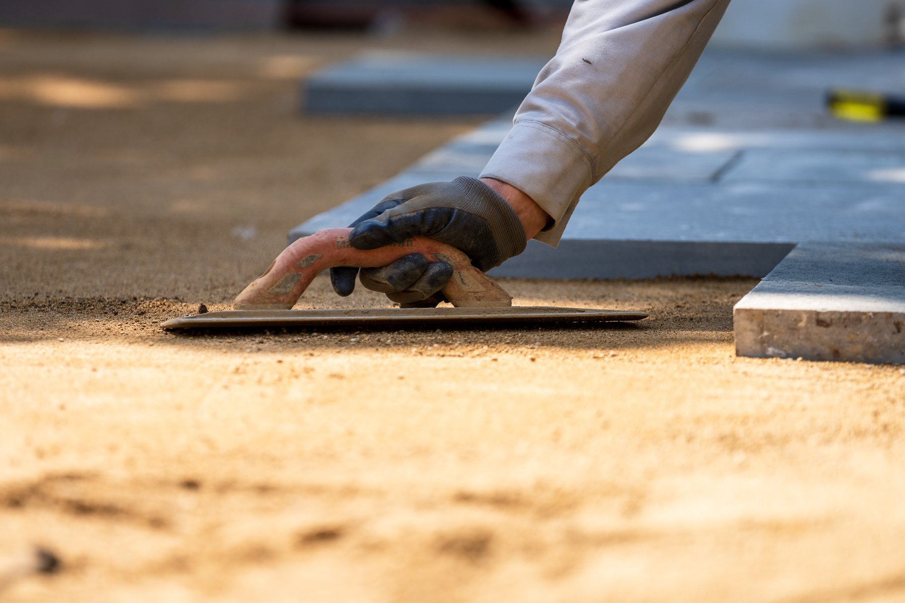 hardscape installer leveling sand for a slab paver installation