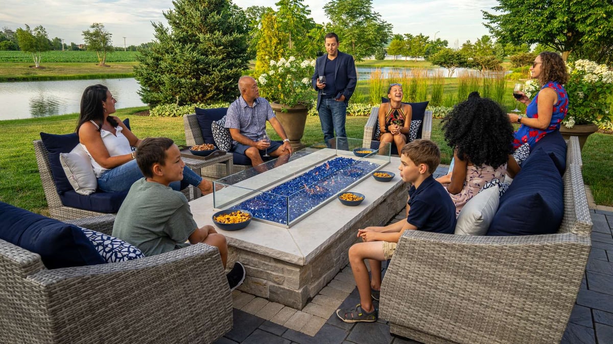 family sit around fire table on outdoor patio 